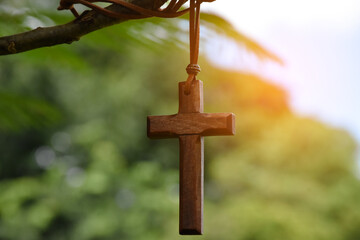 Wooden cross hanging on tree branch, soft and selective focus, natural bokeh tree background, concept for hope, love, forgiveness and belief in Jesus around the world.