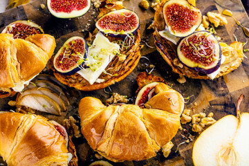 top view of tasty homemade croissants with figs, pears, nuts and honey