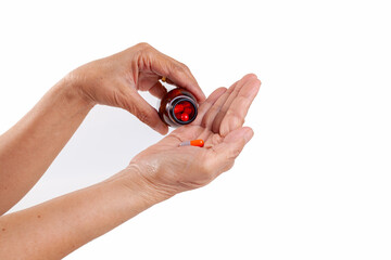 elderly woman pouring pills from a bottle into her hand.