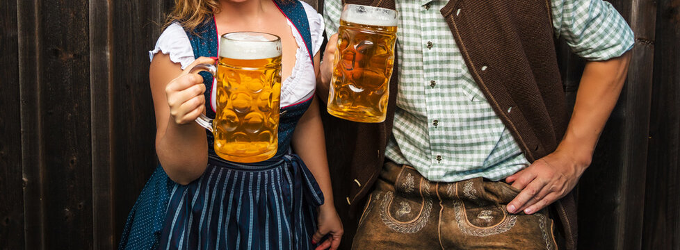 Oktoberfest, woman and man in Bavarian costume with beer mugs