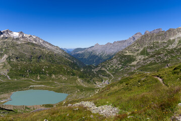 Naklejka na ściany i meble Beautiful scenic aerial view of mountain panorama at Swiss mountain pass Susten with glacier lake on a sunny summer day. Photo taken July 13th, 2022, Susten Pass, Switzerland.