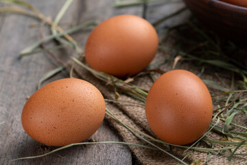 Brown chicken eggs lie on the background of hay and old boards.