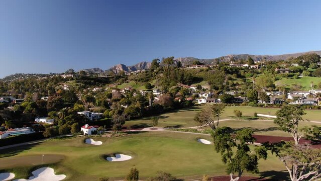 Wide aerial of Montecito golf course and luxury homes with mountain backdrop