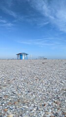 Obraz premium Empty beach with a single blue sea house under clear blue sky