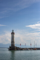 White big lighthouse on the Bodensee Lindau Germany with pier and flags reflecting in the water