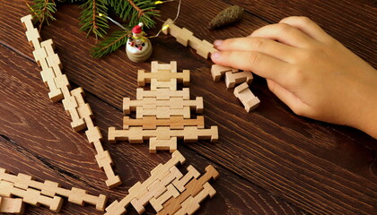 wooden puzzle constructor in children's hands while playing close-up on a wooden table selective focus