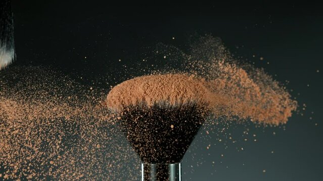 Super slow motion of makeup brushes with flying brown powder. Filmed on high speed cinema camera, 1000fps. Speed ramp effect.