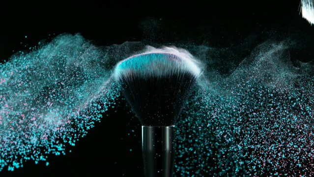 Super slow motion of makeup brushes with flying colored powder. Filmed on high speed cinema camera, 1000fps. Isolated on black background. Speed ramp effect