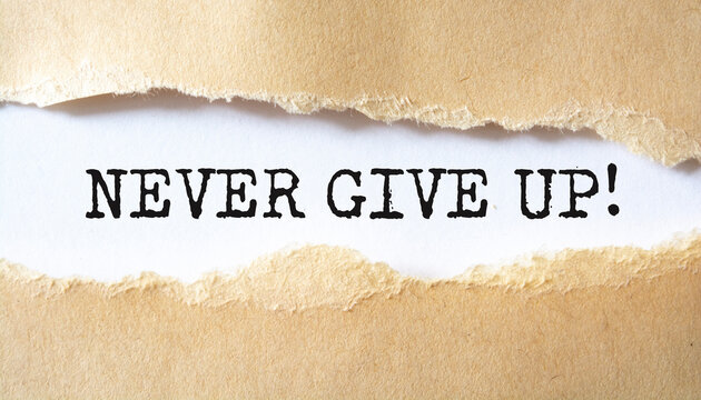 NEVER GIVE UP written under torn paper.