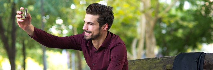 Young smiling businessman taking selfie in the spring park