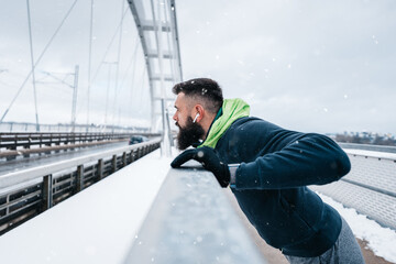 Handsome middle age man with a beard running and exercising outside on extremely cold and snowy day. Sport and fitness motivation theme.