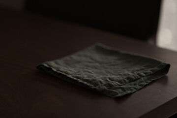 Dark green linen napkin on walnut table indoor with natural window light