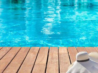 Chapeau de paille sur plage bois de piscine bleue 