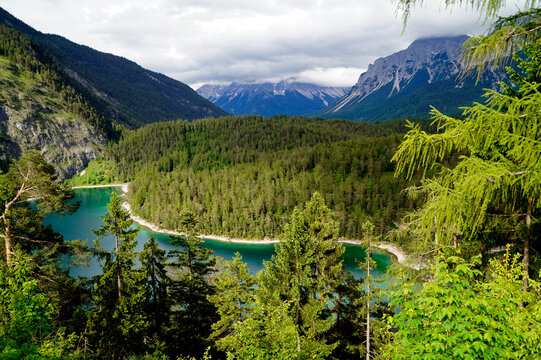 scenic emerald-green alpine lake Blindsee surrounded by the lush green forest at the foot of the Fernpass connecting Austria to Germany (Tyrol, Austria)