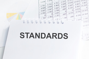 STANDARDS text on notepad in background of document reports on the table