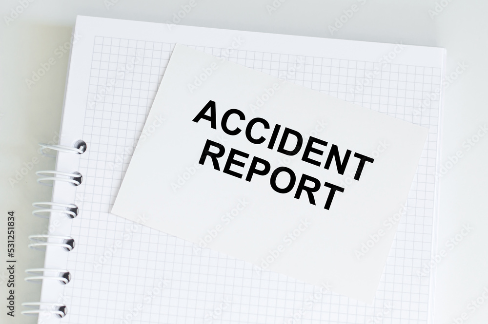 Aufkleber accident report text on a card on the background of a notebook on the table, business concept