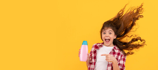 happy teen girl with long curly hair hold shampoo bottle, keratin. Banner of child girl hair care, studio poster header with copy space.