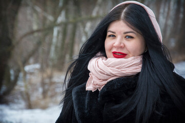 In winter, on a frosty cold day, a girl is standing in the forest.