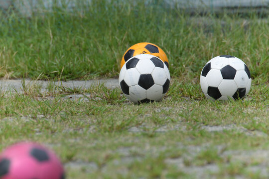 グランド脇の雑草に転がる4個のサッカーボール