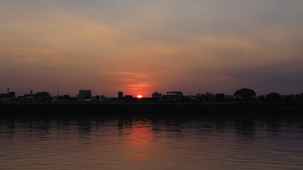 Fototapeta premium Orange sky sunset background by the river There are shadows of trees and churches.