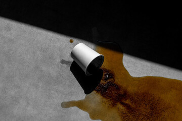 Spilled blank coffee paper cup on concrete background, with sharp natural sunlit shadows. Packaging...