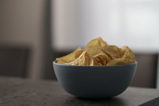 Organic potato chips with black pepper in blue bowl on counterttop
