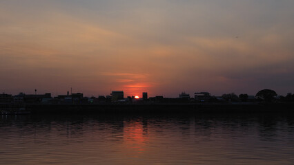 Fototapeta premium Orange sky sunset background by the river There are shadows of trees and churches.