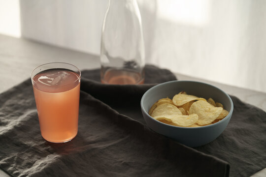 Pink drink with potato chips in a bowl on linen napkin