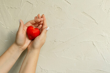 Ripe tomato in the shape of a heart in hands. Healthy food on grey concrete background. Funny,...