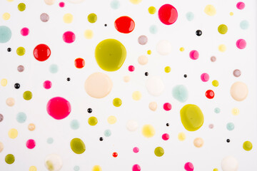 Top view of multi-colored drops on white background.
