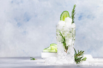 Fototapeta Gin tonic with fresh cucumber, long drink cocktail with dry gin, rosemary, tonic and ice. Gray background, copy space obraz