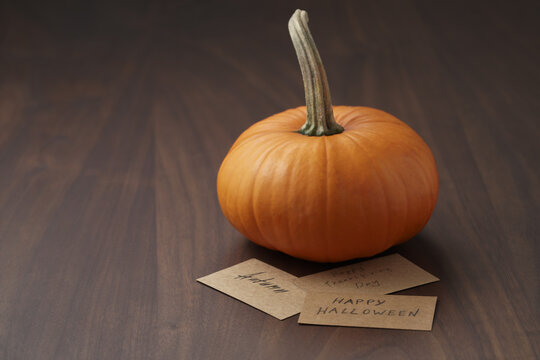 Small orange pumpkin on walnut wood table with copy space