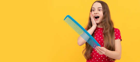 amazed teen girl has long hair hold hair brush on yellow background, haircareback to school. Kid girl hair care, horizontal poster. Banner header with copy space.