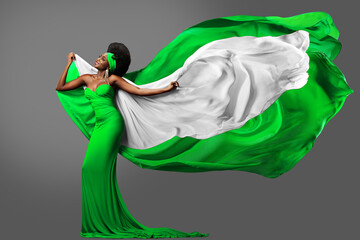 Woman dancing with Nigerian Flag in Green White Dress. Fashion Model with Afro Hair in Long Gown...