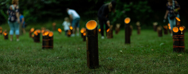 Hundreds of Japanese bamboo lanterns - candles in bamboo stands - flickeringly illuminate the dark, in the style of the traditional Japanese festival of lights Tatsunokuchi Take-toro