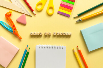 Back to school background. School accessories on a yellow background. Wooden blocks with letters