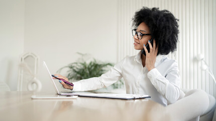 Obraz premium A female secretary is working on a project online, using a laptop, answering the phone.
