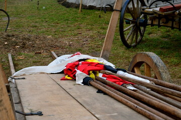 A view of a set of banners, crests, and polearms gathered on a wooden cart made out of planks,...