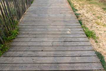 Naklejka premium Old wooden plank footbridge leads over the dune