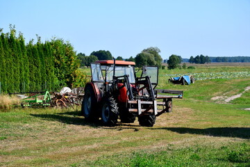 A close up on a red tractor with harvesting attachment and offroad tires standing in the middle of...