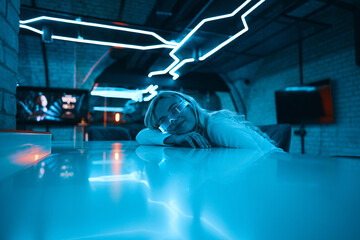 Neon blue light falls on a young woman wearing futuristic glass glasses.