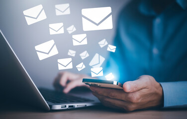 Businessman holding smartphone with communication icons, letter icon, email icons, and newsletter...