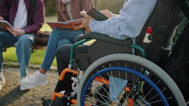 Man sits in wheelchair learning subject with friends
