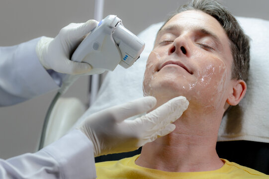 A white man gets a laser facial by a specialist.