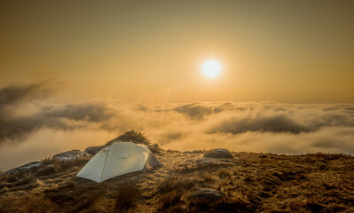 Tent camping on the mountains at the sunset and sunrise landscape with clouds and sun feeling freedom and good vibes