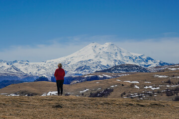 Panorama of Mount Elbrus against the backdrop of the Main Caucasian Range. bckview of a woman, Karachay-Cherkessia. Russia.