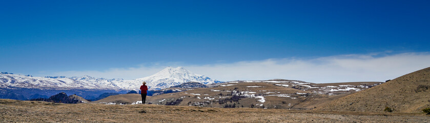 Panorama of Mount Elbrus against the backdrop of the Main Caucasian Range. backview of a woman, Karachay-Cherkessia. Russia.