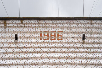 The inscription 1986 is laid out of bricks on the wall of an old Soviet building.