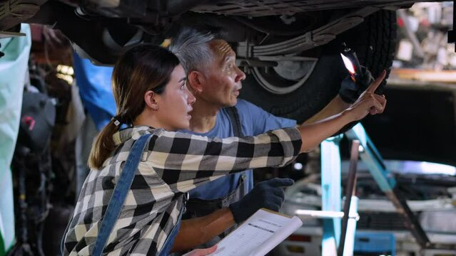 Asian Female trainee Mechanics Working Underneath Car Together Car maintenance and auto service garage. Car maintenance and auto service garage concept.