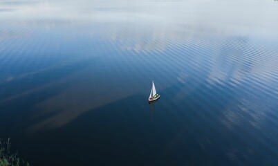 Drone shot of a small sailing boat on the water with the reflection of sky - great for wallpaper